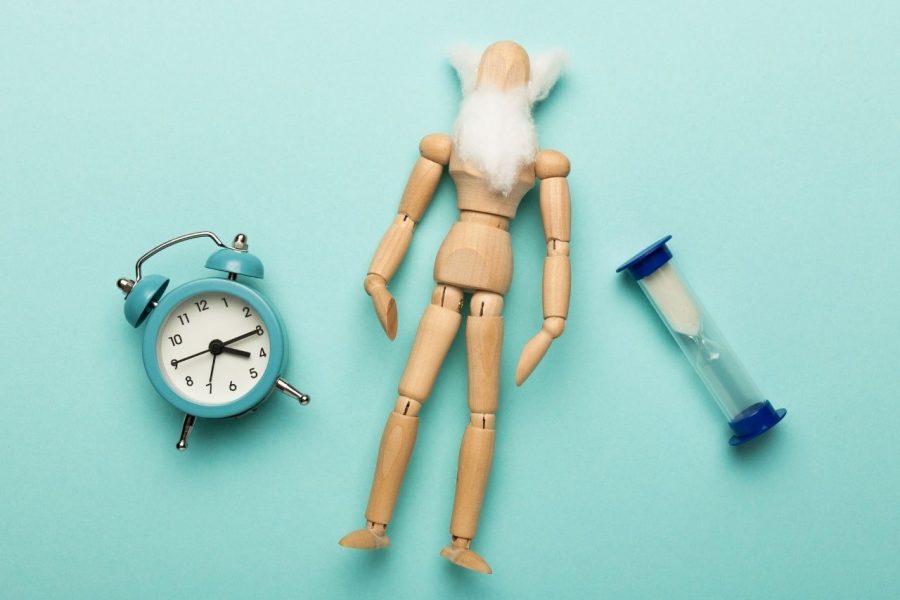 Concept of Ageing and old age. Miniature wooden man with clock and sand clock depicting importance of time in money management