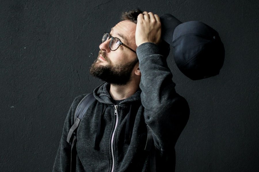 Picture of a man in black background holding a cap and thinking_ feature image for Thinking-Wealth-Blog_Investing: Give, Take, Make, and the In-Betweens